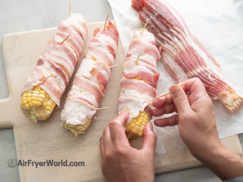 Wrapping bacon around corn ears