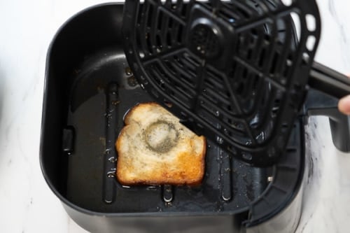 Lifting air fryer tray to remove bread slice