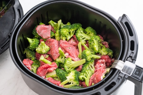 Raw beef and broccoli in air fryer basket