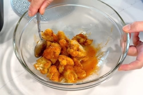 Tossing the air fried cauliflower with buffalo sauce