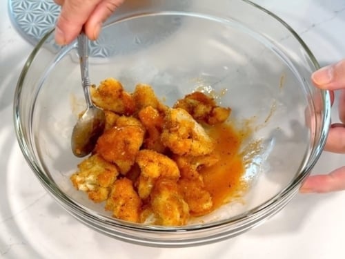 Tossing the air fried cauliflower with buffalo sauce