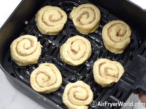 Uncooked cinnamon rolls in air fryer basket