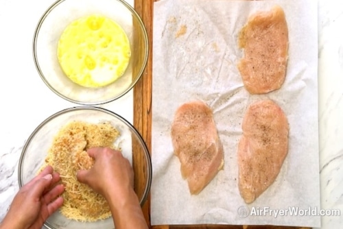 Dipping chicken breasts into beaten egg and bread crumb mixture