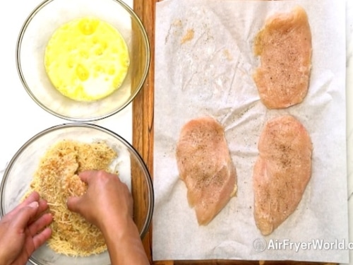 Dipping chicken breasts into beaten egg and bread crumb mixture