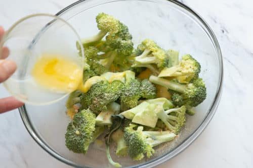 Pouring egg over seasoned broccoli
