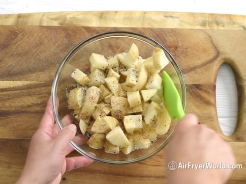 Seasoning potatoes in bowl