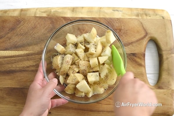 Seasoning potatoes in bowl