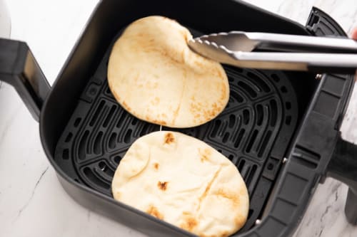Flipping the flatbreads over in air fryer basket