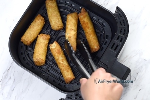 Turning egg rolls with tongs
