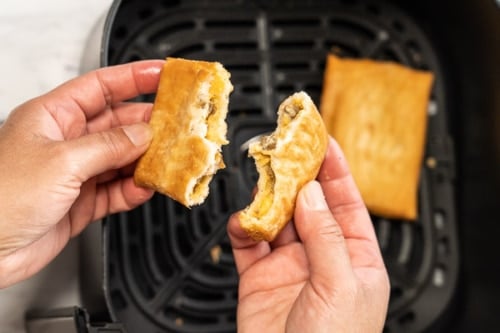 Cooked toaster scramble being broken in half by hand