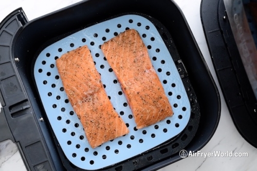 Raw salmon in air fryer on a perforated silicone mat