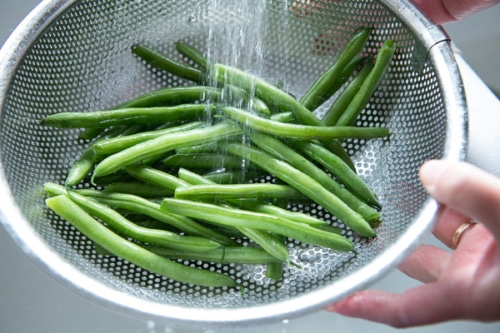 Rinsing green beans in a colander