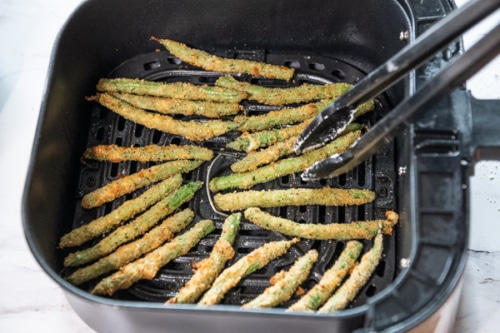 Turning partially cooked green beans with tongs