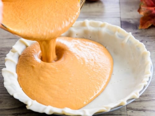 Pouring pie filling into uncooked pie crust