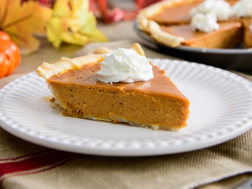 Slice of pumpkin pie on a plate with whipped cream