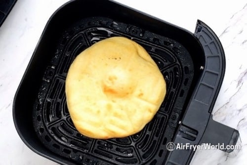 Cooked pizza crust in air fryer basket