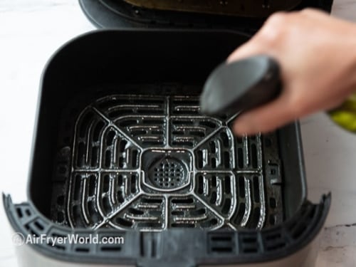 Spraying air fryer basket with oil