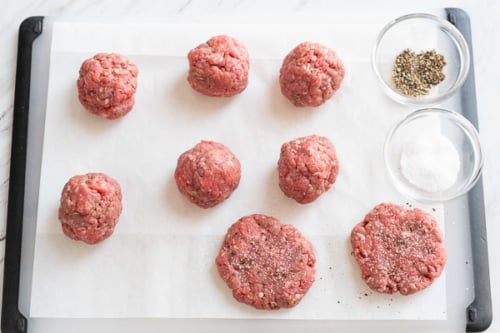Balls of beef mixture and patties on a cutting board