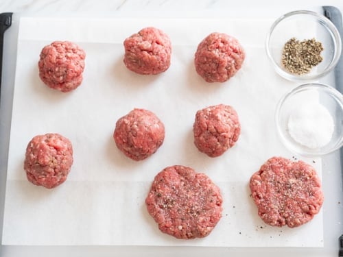 Balls of beef mixture and patties on a cutting board