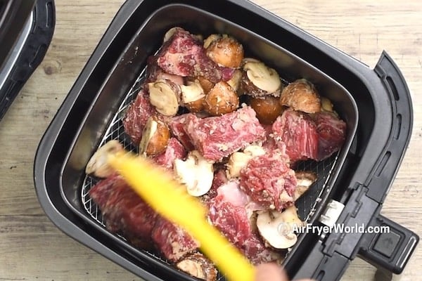Uncooked beef and mushrooms in air fryer basket