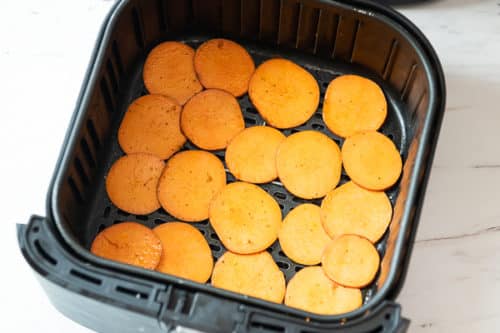 Uncooked sweet potato slices in air fryer basket