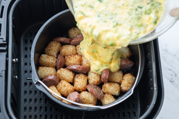 Add egg to air fryer with sausage and tater tots