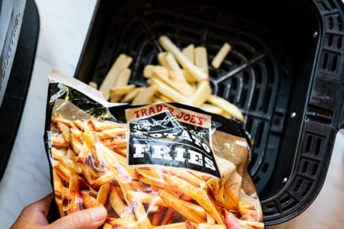 Pouring trader joes handsome cut potato fries in air fryer basket