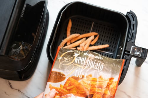 Bag of trader joes frozen sweet potato fries pouring into air fryer basket