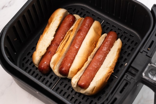 Cooked hot dogs in buns and in air fryer basket
