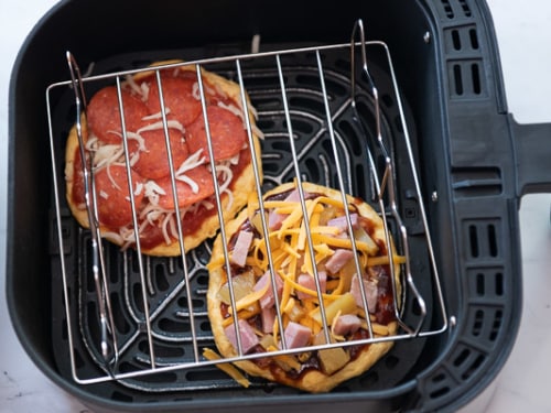 Rack over the top of the pizzas to keep toppings from flying off