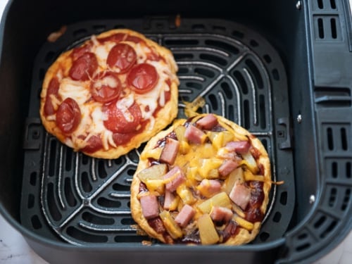 Cooked biscuit dough pizzas in air fryer basket