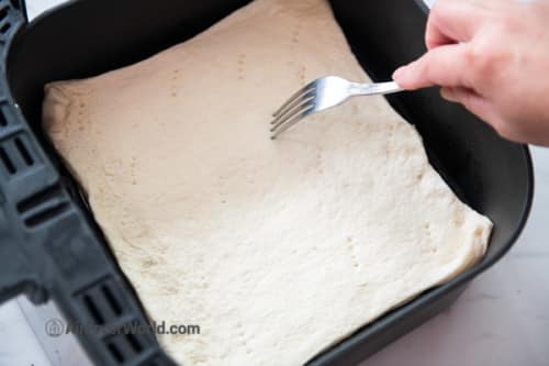 Poking holes in pizza dough with a fork