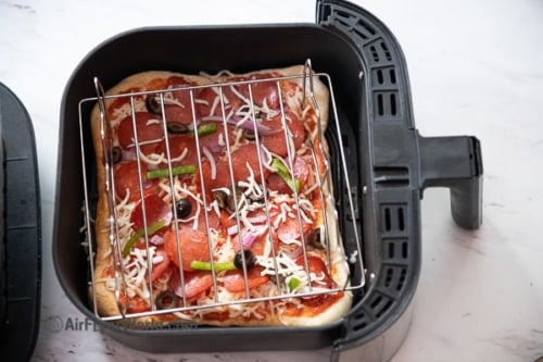 Pizza in air fryer with rack over toppings