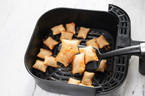 Cooked regular frozen pizza rolls on a spatula over air fryer