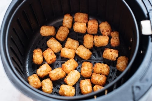 Cooked tater tots in air fryer basket