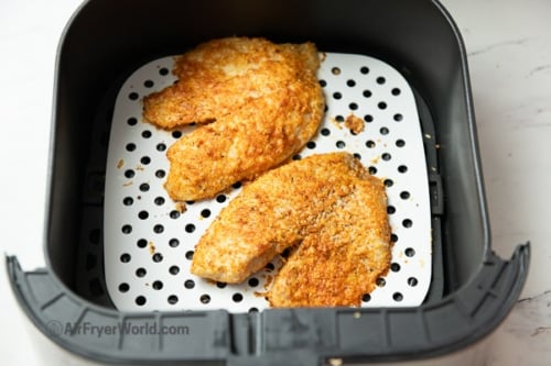 Cooked coated fish fillets in air fryer basket