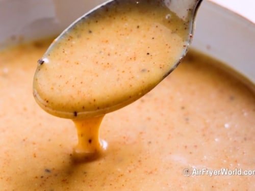 Spoonful of honey mustard sauce pouring down