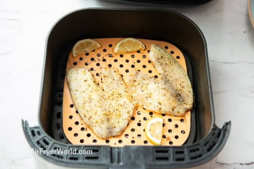 Cooked tilapia filets in air fryer basket