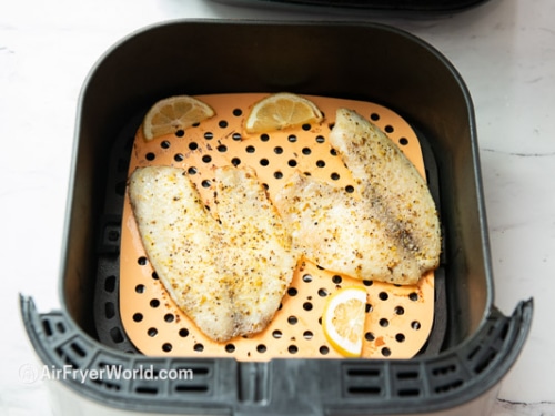 Cooked tilapia filets in air fryer basket