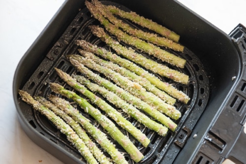 Uncooked asparagus in a single layer in air fryer