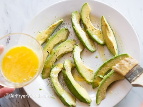 Brushing egg on avocado slices