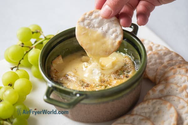 cracker dipping into cheese