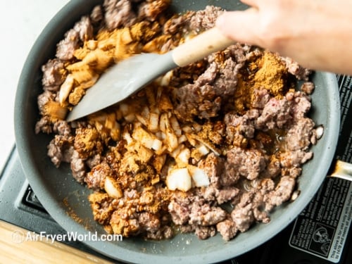 adding onion and taco seasoning to beef mix