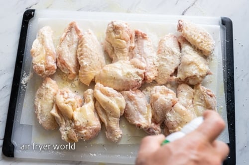 Spraying chicken wings with oil