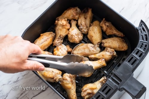 Turning the chicken wings with tongs
