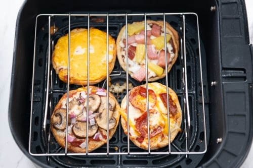 English muffin pizzas covered with wire rack
