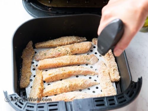 spraying oil on air fryer fish sticks