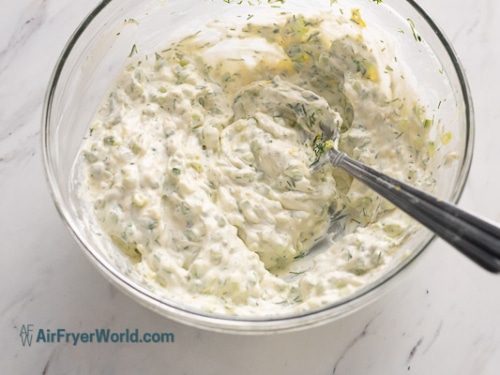 Stirring tzatziki dip in a bowl