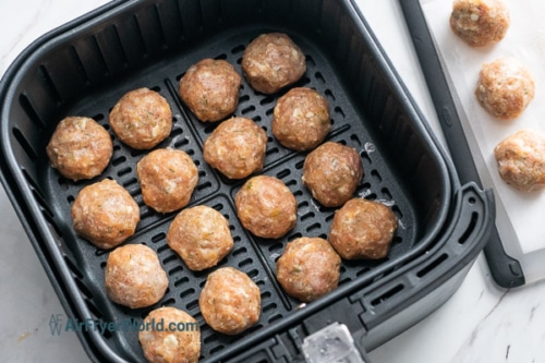 Uncooked meatballs in air fryer basket