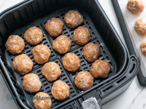 Uncooked meatballs in air fryer basket